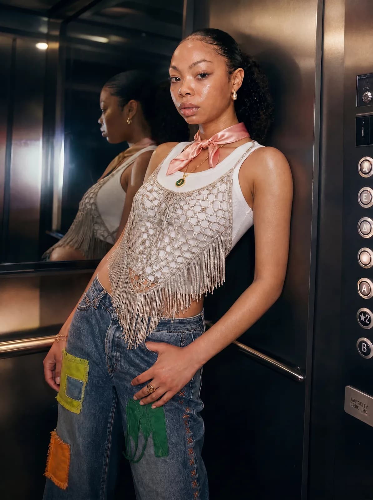 Editorial frame — modelka w stalowej windzie, refleksy lustrzane, patchworkowe jeansy i crochet top